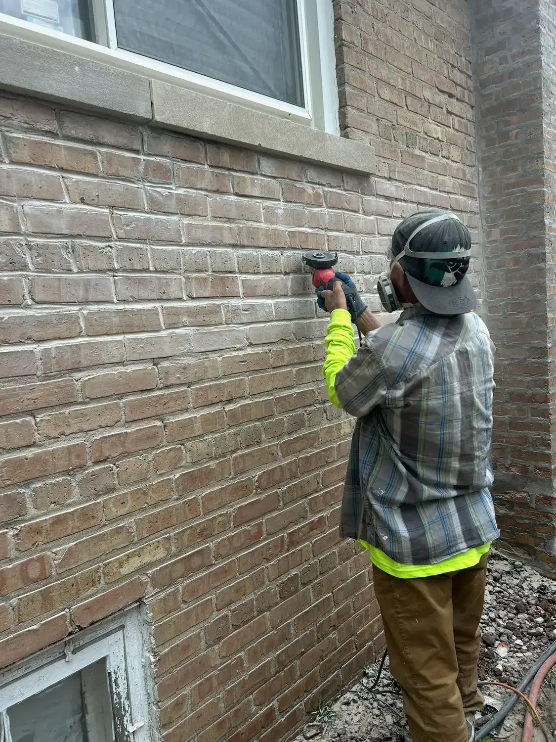 Mason grinding old mortar out of a brick wall in Dolton
